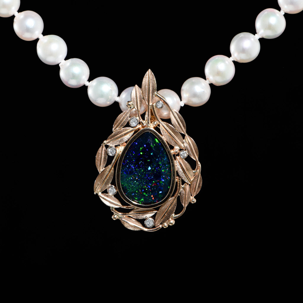A black opal pendant with yellow gold leaves and bezel-set diamonds on a pearl necklace.