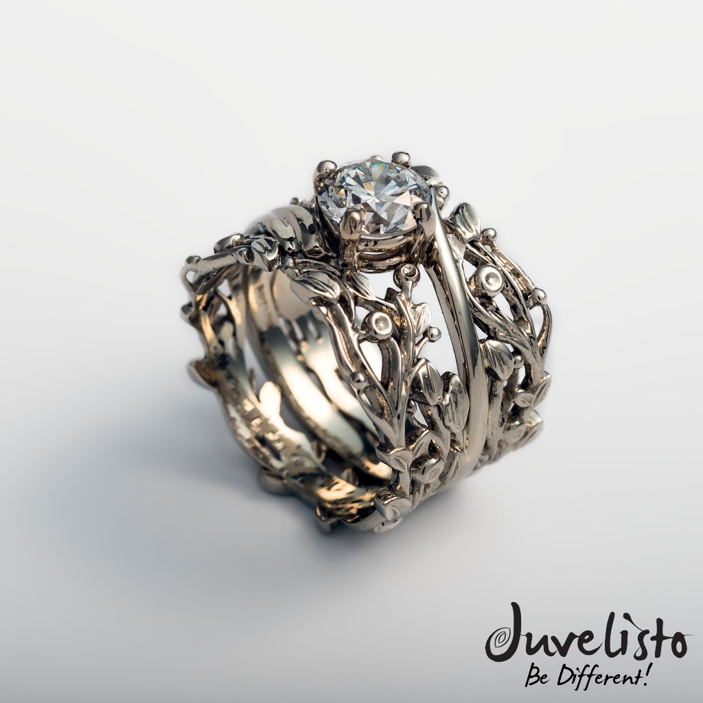 gold ring with intricate design and central diamond on a light gray background, Juvelisto brand visible.