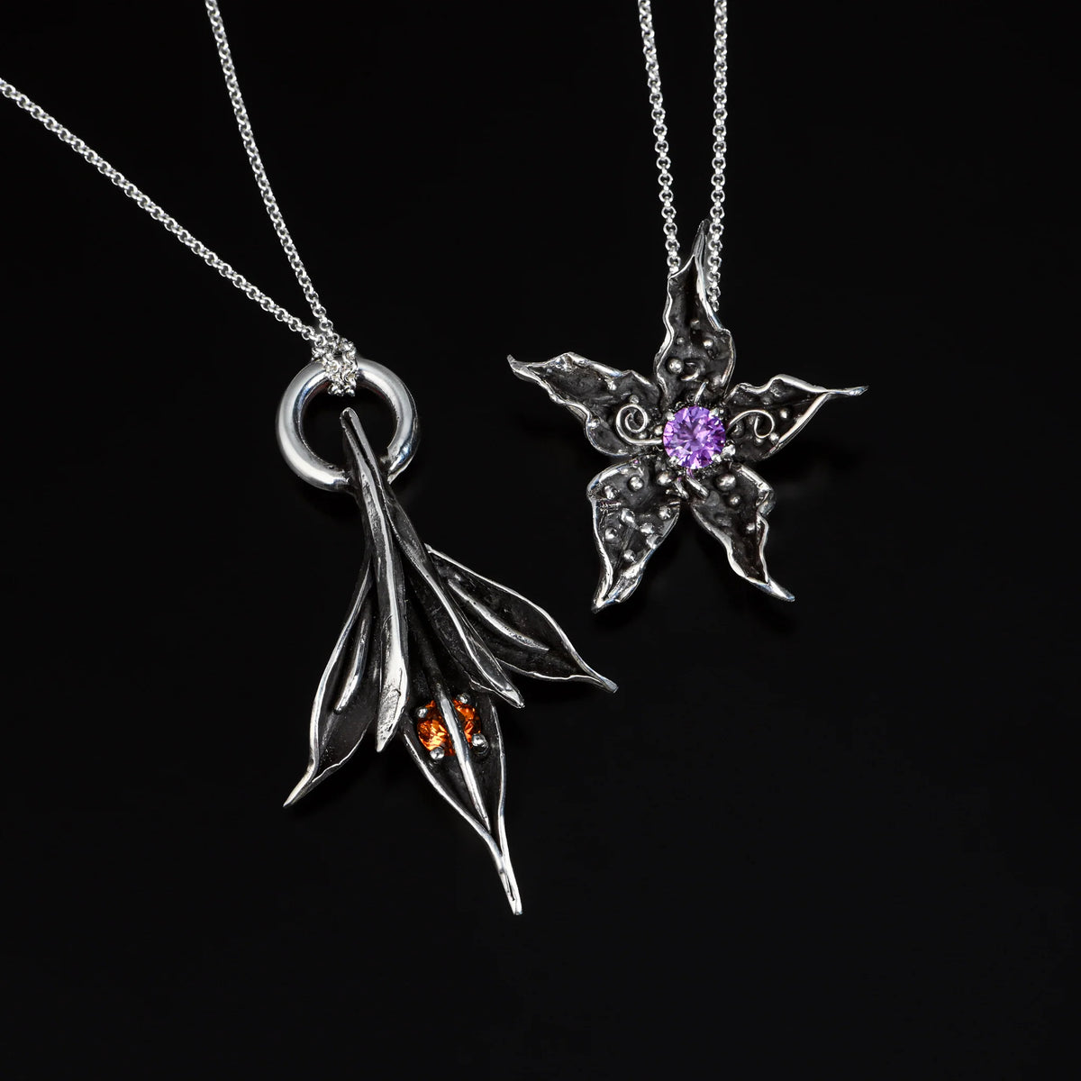 Two silver leaf-shaped pendants on black background