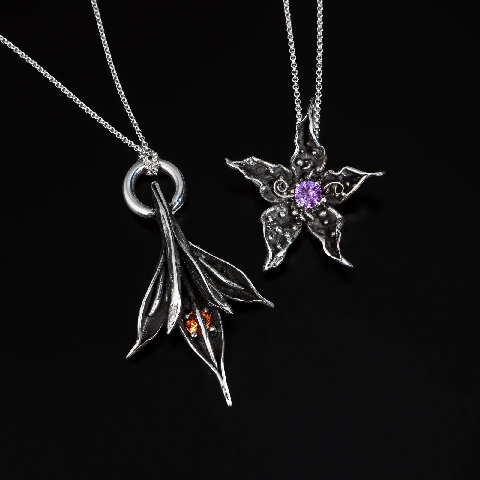 Two silver leaf-shaped pendants on black background