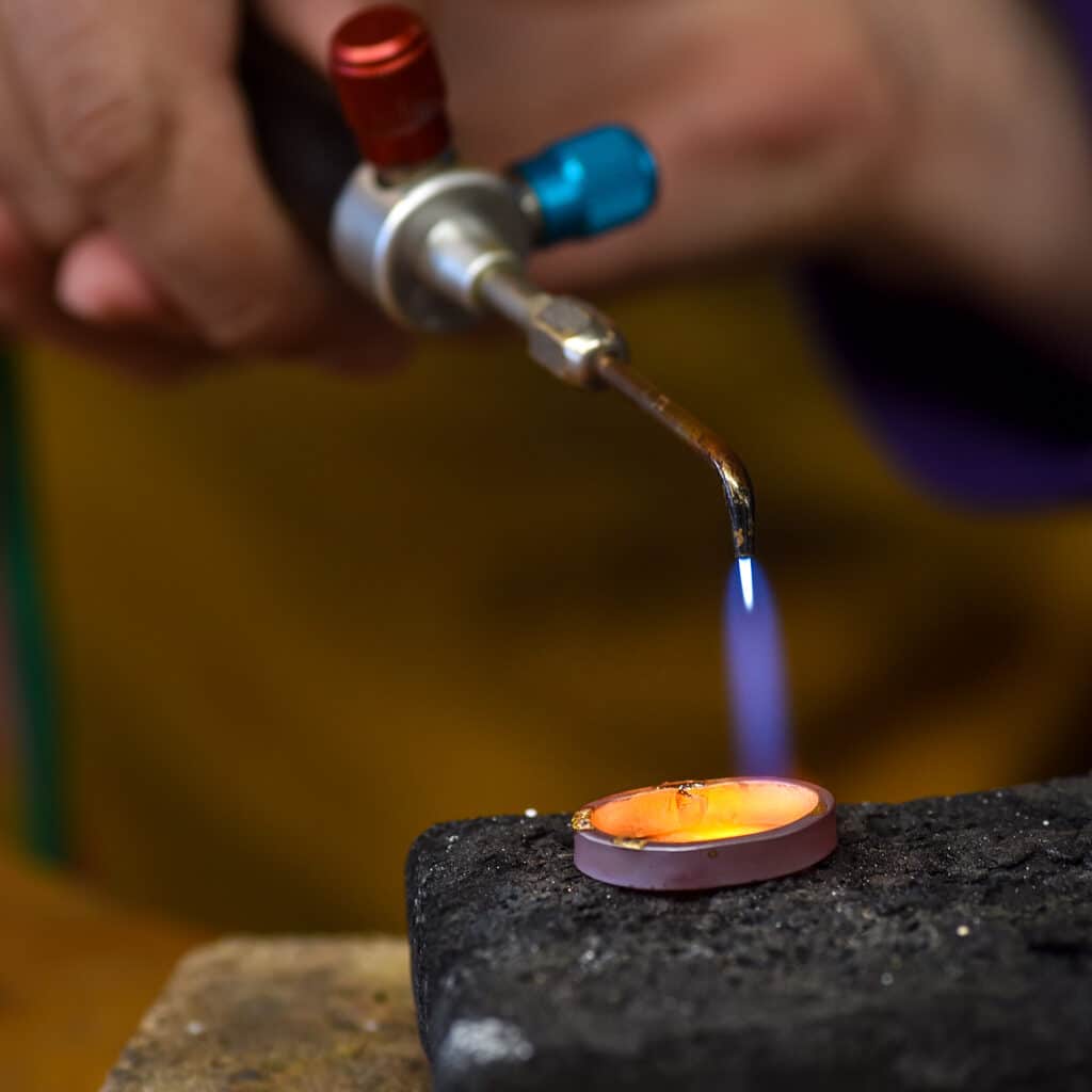 A torch heating a wedding band during hand fabrication