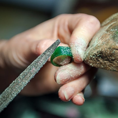 A green wax ring being shaped with a hand file